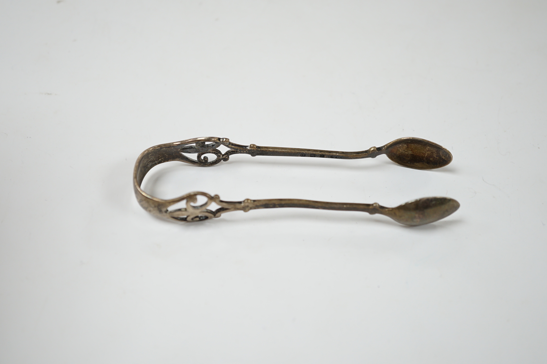 A George V silver three piece condiment set by S.W. Smith & Co, Birmingham, 1917/8/9 and a pair of silver tongs.